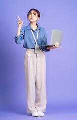 Photo of young Asian businesswoman holding laptop on background