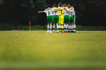Group of teenage school boys huddling united in soccer team before the final football match. Boys...
