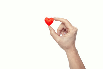 Female fingers hold a tiny red heart. Symbol of love.