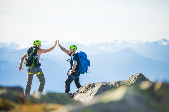 Two climbers hi-five on mountain summit of Douglas Peak, B.C., Canada.