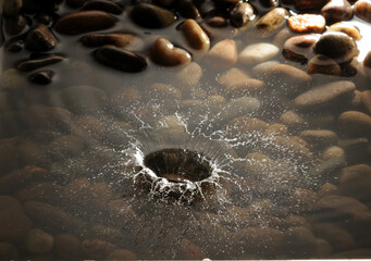 A pebble dropping into a shallow stony pool.