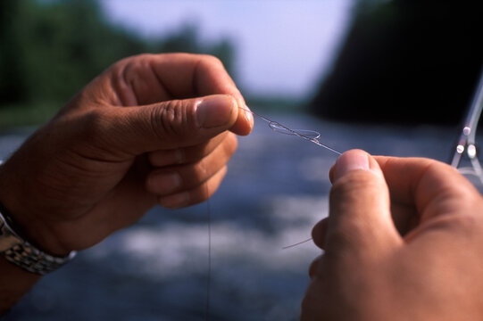 A fisherman attaches a new leader to a fly line while fishing in the Kennebec River near Greenville, Maine.