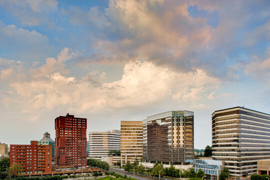 Clouds drift over a line of office buildings late on a summer afternoon.