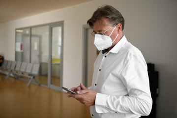 man in protective mask in office using smartphone