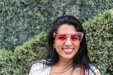 Portrait of a young woman with a smile and sunglasses in the city.