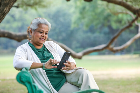 Indian Senior Woman Using Smartphone At Park.