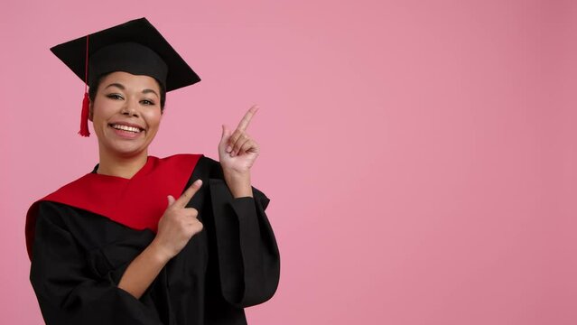 Portrait of a joyful student getting her college diploma. Close-up of a cheerful student in a hat and gown. Copy space on pink background. High quality 4k footage
