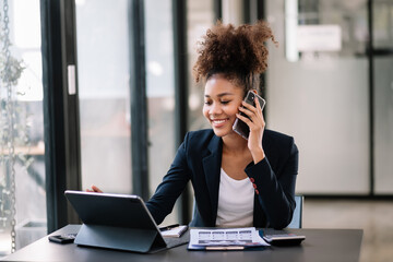 Business Africa woman Talking on the phone and using a laptop with a smile while sitting at modern office