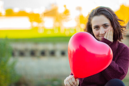 Mujer Joven De Raza Caucásica Con El Pelo Corto Sujetando Con Una Mano Un Globo Rojo Con Forma De Corazón Que Le Han Regalado Por El Día De San Valentín.