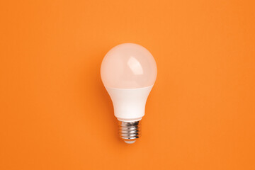 LED lamp on a orange background. Energy saving concept, alternative energy sources, idea