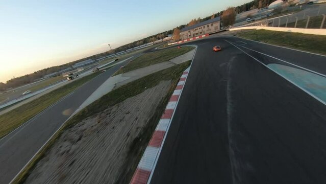 aerial filming of a circuit race on an asphalt circuit, fpv drone, racing cars go fast, time trials, sharp turns