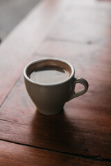 A cup of black strong coffee on a wooden table. Hot Americano