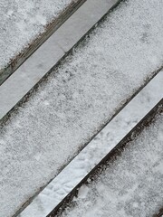 Fototapeta premium Close up of wooden rustic bench in the snow with copy space. First snow. Winter is coming concept. Creative diagonal line background. Website banner.