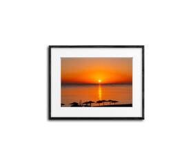 Black frame with picture of colorful sunrise over the sea isolated on white wall