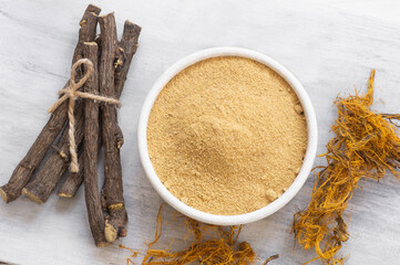 Licorice root, licorice fiber and powder in bowl  on rustic background ( glycyrrhiza glabra )