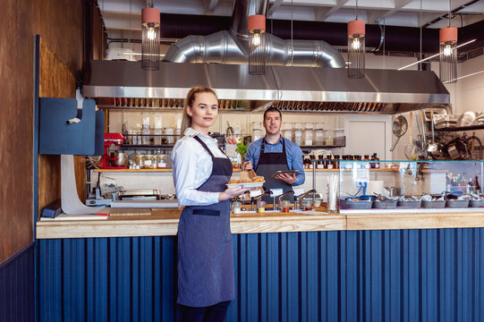 Smiling small business owners serving food in new fast food restaurant