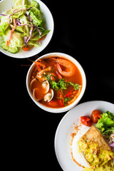 Lunch set made of tom yum soup, salad, grilled basa fish, rice, on black background