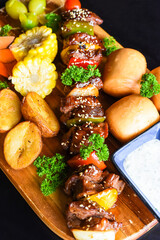 Beef skewers with pepper and corn served with vietnamese buns on black background top view