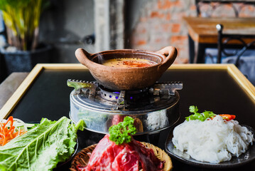 Korean spicy hot pot with beef meat and noodles on black background