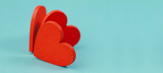 Three red wooden hearts on a blue background with space for a copy. Macro photography, Valentine's Day card, Mother's Day, March 8, wedding. The concept of celebration, happiness, love.