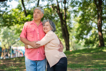 Portrait of lovely elderly couple hugging each other with love and happiness in a park outdoor. Happy smiling Elderly couple enjoying with positive emotions at garden
