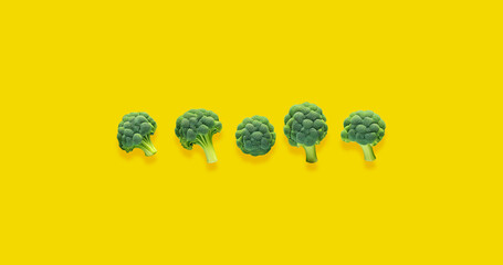 Five broccoli on yellow background Vegan food Space for text Yellow background Healthy food 