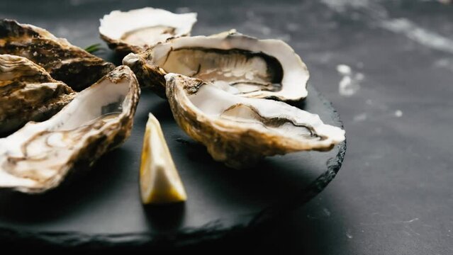 Raw luxury oysters with lemon and rosmarine for romantic dinner. Man and woman take seafood from platter