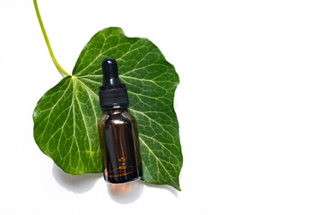 A jar of amber glass and a natural green leaf on a white background. Top view, space for text.