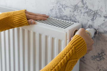 Man adjusting heating radiator or heater to install comfort temperature for energy efficiency and economy in winter