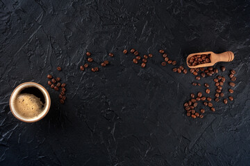 Coffee cup and beans, overhead flat lay shot on a black slate background with a place for text,...