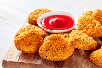 Chicken nuggets with ketchup close-up on a wooden board. A crispy snack at a restaurant, a fast food dish