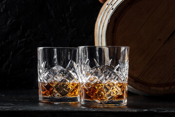 Whiskey in glasses with a barrel. Bourbon whisky and a cask on a dark background, a tasting at a...