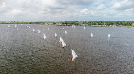 A line of small sailboats in a match on the Sneekermeer