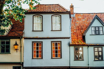 Light Blue old fashion, traditional English house with red clay tile roof and windows. Facade building. Fairy tale houses. Selective focus, copy space.
