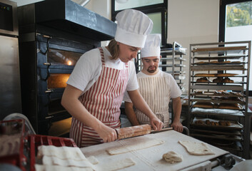 Man with down syndrom helping prepair bread in bakery with his colleague. Concept of integration...