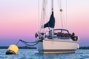 Sailing boat anchored with dramatic sunset and brown dog on deck - obrazy, fototapety, plakaty