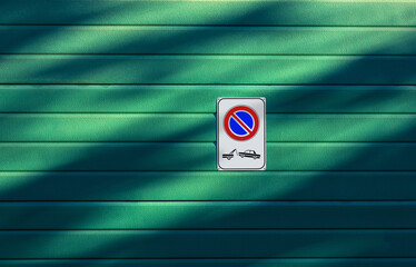 Closeup of a No Parking and Tow Away Zone sign on a green garage door, full frame, photography,...