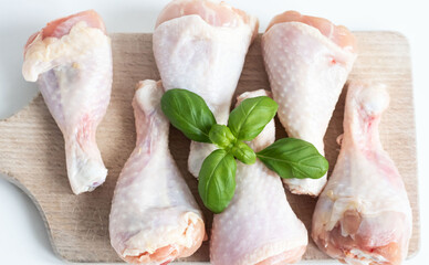 Raw chicken legs. On a white background. Salt, pepper, leaves