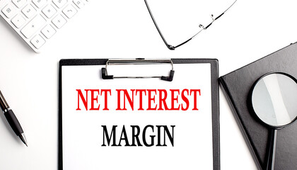 NET INTEREST MARGIN text written on paper clipboard with office tools
