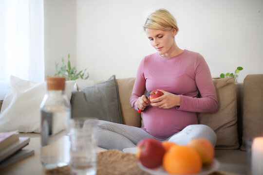 High angle view of pregnant woman cutting apple.