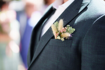 a dried flower boutonniere in the pocket of a man's jacket. 