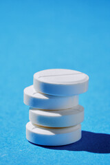 Pharmacy healthcare and drugs concept. Macro of four white tablets small tower on blue background.