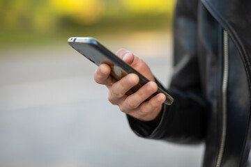 Unrecognizable man holding mobile phone in hand, blurred background