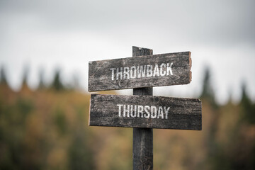 vintage and rustic wooden signpost with the weathered text quote throwback thursday, outdoors in nature. blurred out forest fall colors in the background. - 561811386