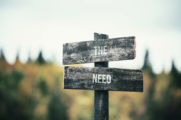 vintage and rustic wooden signpost with the weathered text quote the need, outdoors in nature. blurred out forest fall colors in the background.