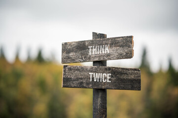 vintage and rustic wooden signpost with the weathered text quote think twice, outdoors in nature....
