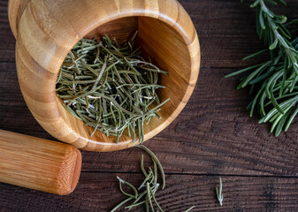 Dried rosemary leaves in a wooden mortar. Spices to add to dishes.