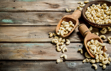 Cashews in a bowl with a wooden scoop.
