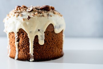 Easter holiday. Raisin cake with white chocolate glaze and nuts on a light background