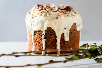Easter attributes. Orthodox holiday.A cake with a white chocolate glaze and nuts on a light background next to a willow twig